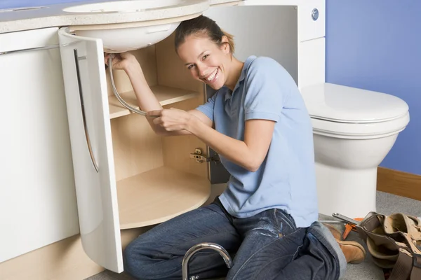 Rörmokaren arbetar på diskbänken leende — Stockfoto