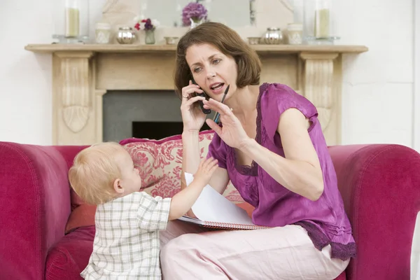 Mère Utilisant Téléphone Dans Salon Avec Bébé Fronçant Les Sourcils — Photo