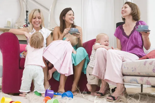 Drie moeders in woonkamer met koffie en baby's glimlachen — Stockfoto