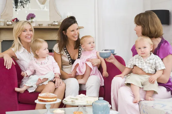Drie moeders in woonkamer met baby's en koffie glimlachen — Stockfoto