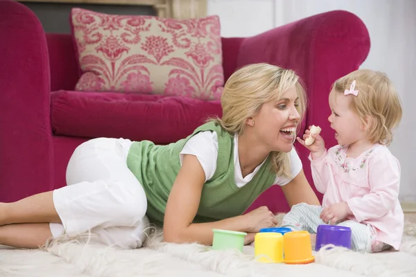 Matka v obývacím pokoji s dítětem jíst banán a usmívá se — Stock fotografie