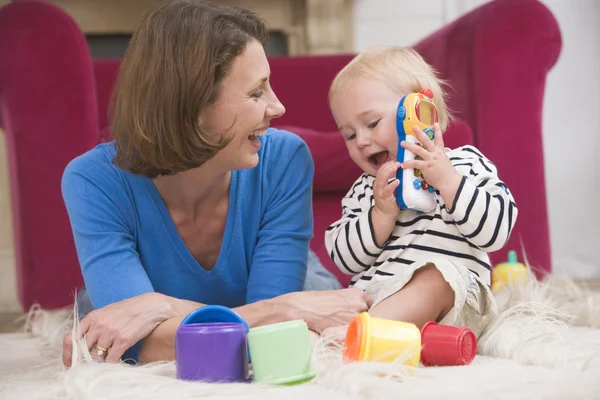 Annesi gülümseyerek bebekle oynarken oturma odasında — Stok fotoğraf