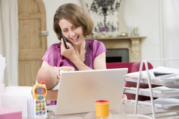 母亲和婴儿的家庭办公室与便携式计算机和电话 — 图库照片
