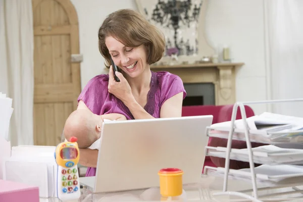 Mãe e bebê no escritório em casa com laptop e telefone — Fotografia de Stock
