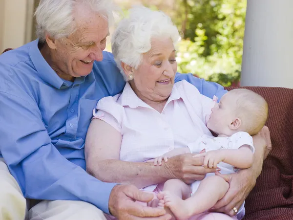 Grandparents outdoors on patio with baby smiling — Stock Photo, Image