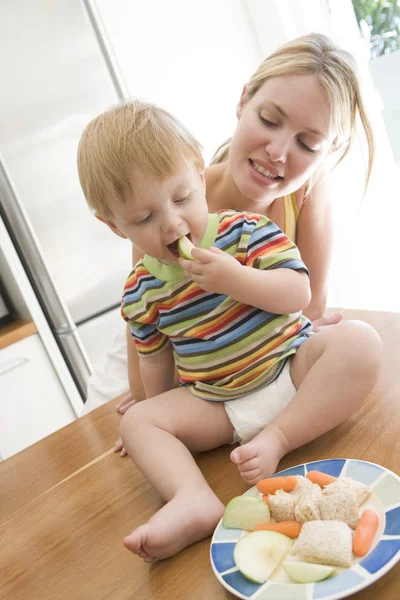 妈妈和宝宝在厨房里吃水果和蔬菜 — 图库照片