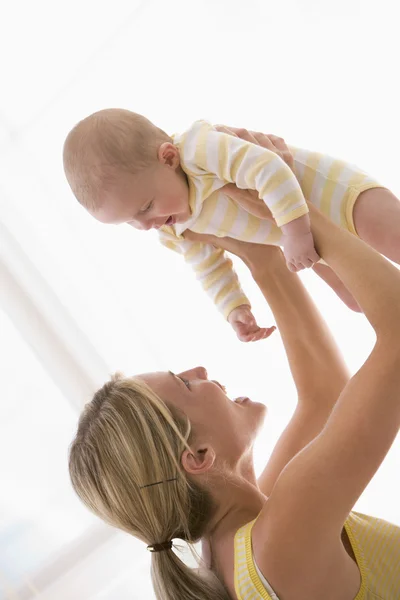 Modern som håller baby inomhus leende — Stockfoto