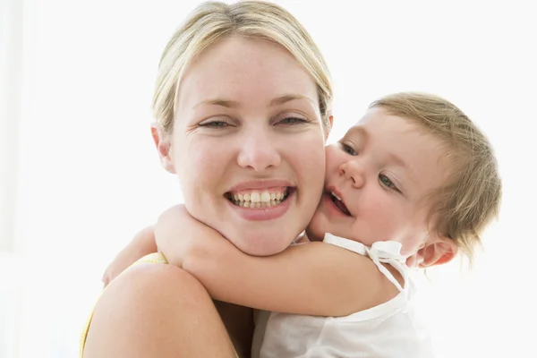 Мать и ребенок в помещении обнимаются и улыбаются — стоковое фото