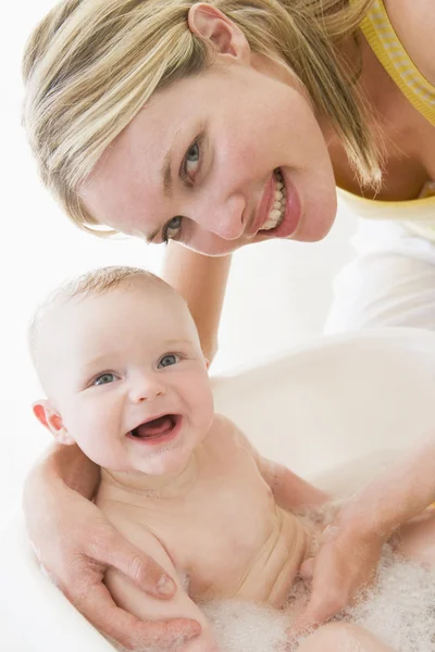 Мама делает ванну с пузырьком, улыбаясь — стоковое фото