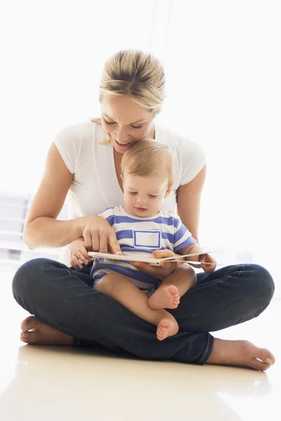 Mãe e bebê dentro de casa lendo livro e sorrindo — Fotografia de Stock