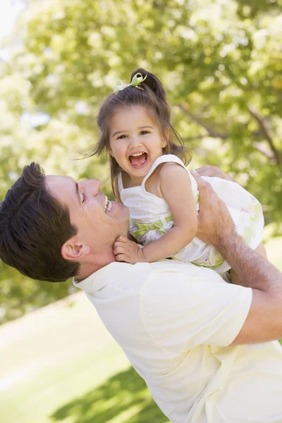 Отец держит дочь на улице улыбаясь — стоковое фото