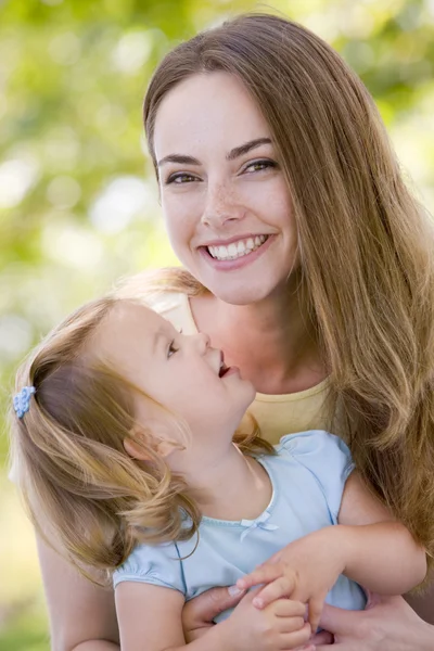 Mãe segurando filha ao ar livre sorrindo — Fotografia de Stock