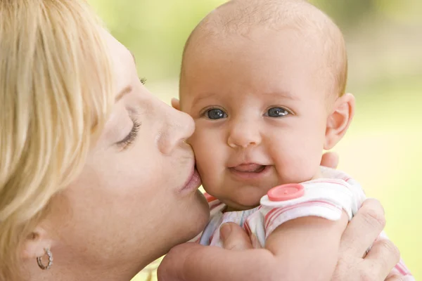 Mãe beijando bebê ao ar livre — Fotografia de Stock