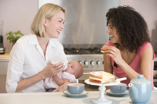 Moeder en baby in keuken met vriend eten taart en glimlachen — Stockfoto
