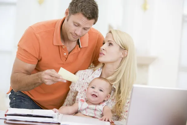Couple and baby in dining room with laptop and paperwork — Stock Photo, Image