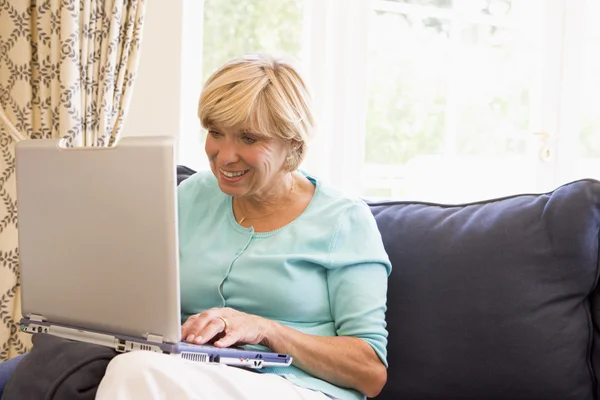 Mulher na sala de estar com laptop sorrindo — Fotografia de Stock