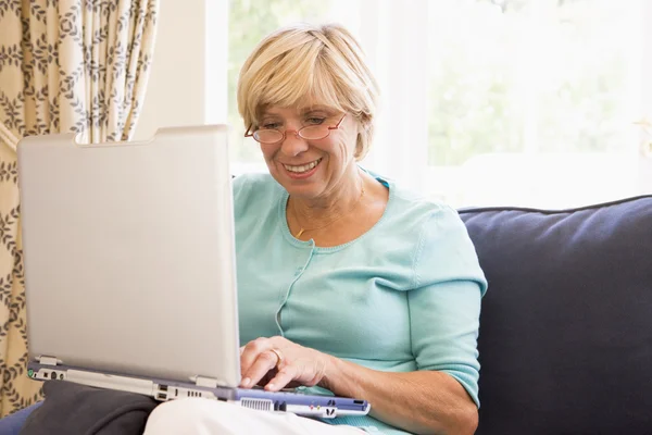 在客厅里用笔记本电脑微笑的女人 — 图库照片