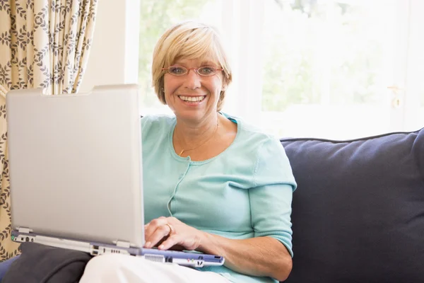 Mujer en la sala de estar con portátil sonriendo — Foto de Stock