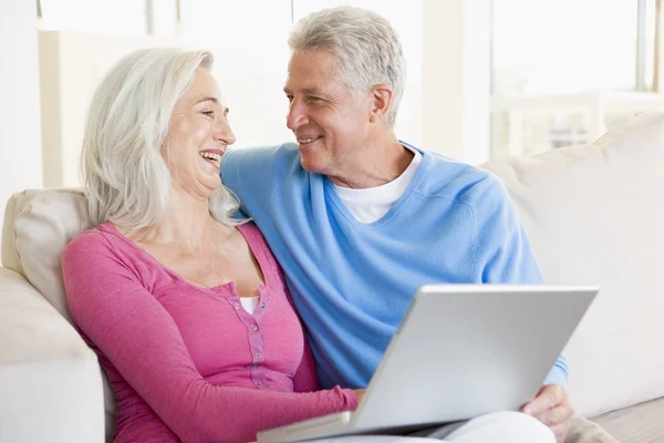 Casal na sala de estar com laptop sorrindo — Fotografia de Stock