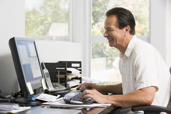 Человек в домашнем офисе за компьютером улыбается — стоковое фото
