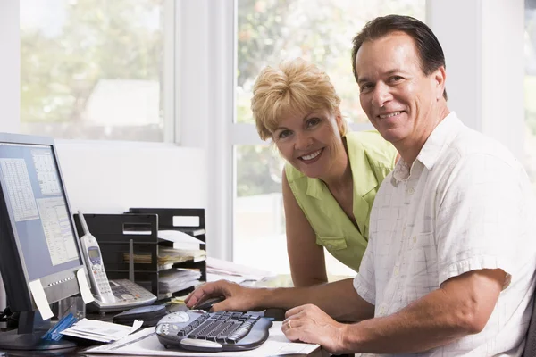 Пара в домашнем офисе за компьютером улыбается — стоковое фото