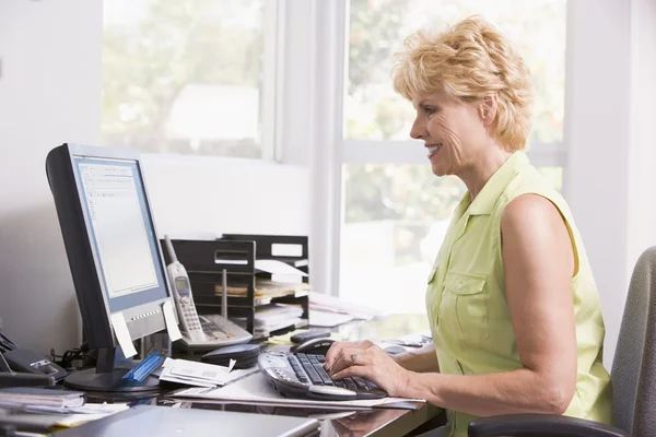 Woman in home office at computer smiling — Stock Photo, Image