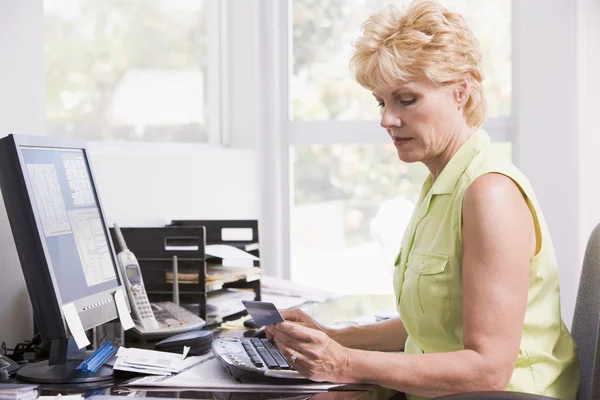 Kvinna i home office på datorn med kreditkort rynkar pannan — Stockfoto