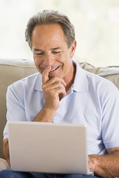 在客厅里用笔记本电脑微笑的男人 — 图库照片