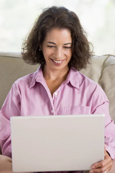 Vrouw in woonkamer met laptop lachende — Stockfoto