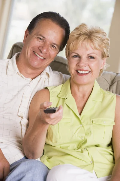 Casal na sala de estar usando controle remoto sorrindo — Fotografia de Stock