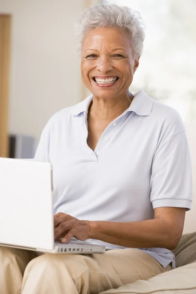 Woman in living room with laptop smiling — Stock Photo, Image