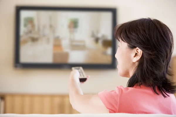Женщина смотрит телевизор с помощью дистанционного управления — стоковое фото