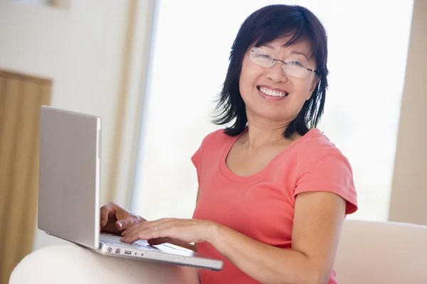 Женщина в гостиной с ноутбуком улыбается — стоковое фото