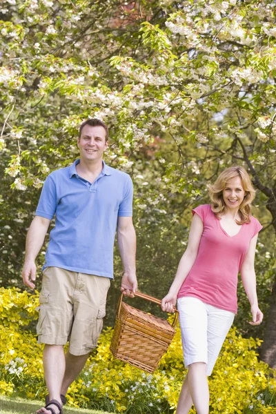Paar geht mit Picknickkorb lächelnd ins Freie — Stockfoto