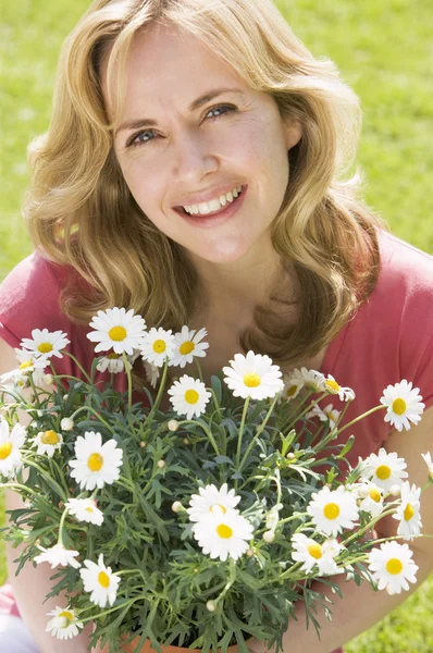 Mujer al aire libre sosteniendo flores sonriendo — Foto de Stock