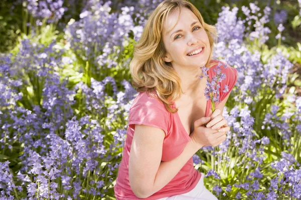 Mujer al aire libre sosteniendo flores sonriendo —  Fotos de Stock