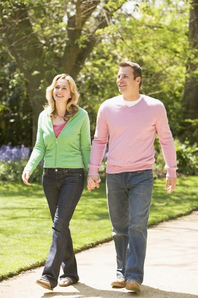 笑みを浮かべて手を繋いでいるパス上を歩いてのカップル — ストック写真