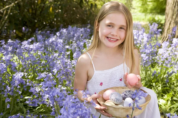 Młoda dziewczyna na zewnątrz gospodarstwa różne jajka w koszyku uśmiechający się — Zdjęcie stockowe