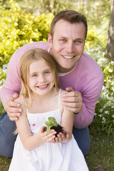 Vater und Tochter im Freien halten Pflanze lächelnd — Stockfoto