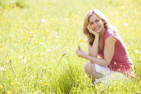 Woman outdoors holding flower smiling — Stock Photo, Image