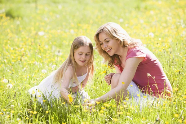 Madre e hija al aire libre sosteniendo la flor sonriendo —  Fotos de Stock