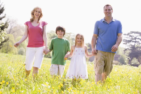Family walking outdoors holding flower smiling — Stock Photo, Image