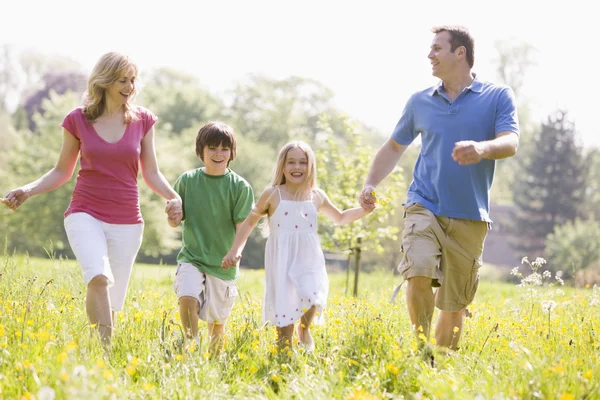 Familie lopen buiten houden handen glimlachen — Stockfoto
