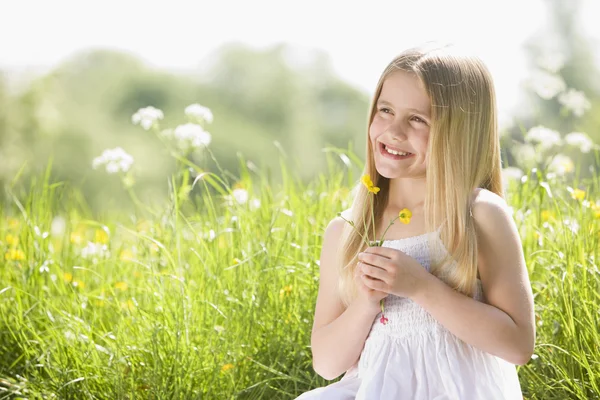 Νεαρό Κορίτσι Που Κάθεται Εξωτερικούς Χώρους Κρατώντας Χαμογελώντας Λουλούδι — Φωτογραφία Αρχείου