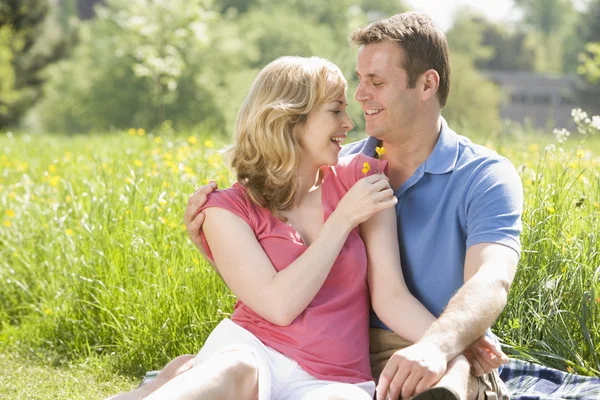 Paret sitter utomhus håller blomma leende — Stockfoto
