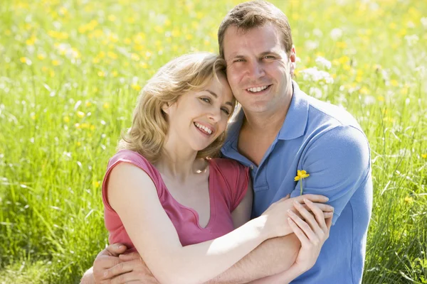 Paret sitter utomhus håller blomma leende — Stockfoto