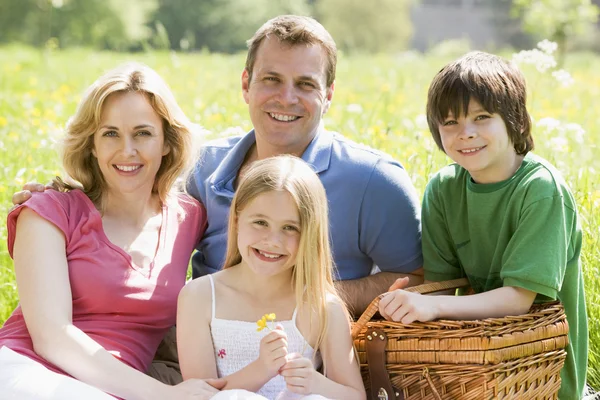 Familia sentada al aire libre con cesta de picnic sonriendo —  Fotos de Stock