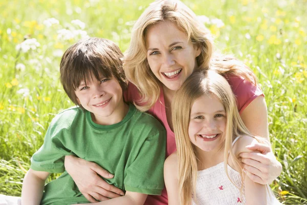 母亲和两个小孩坐在户外微笑 — 图库照片