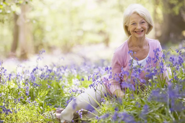 Açık havada çiçekler gülümseyerek oturan kadın — Stok fotoğraf