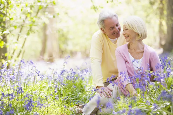 Couple sitting outdoors with flowers smiling — Stock Photo, Image